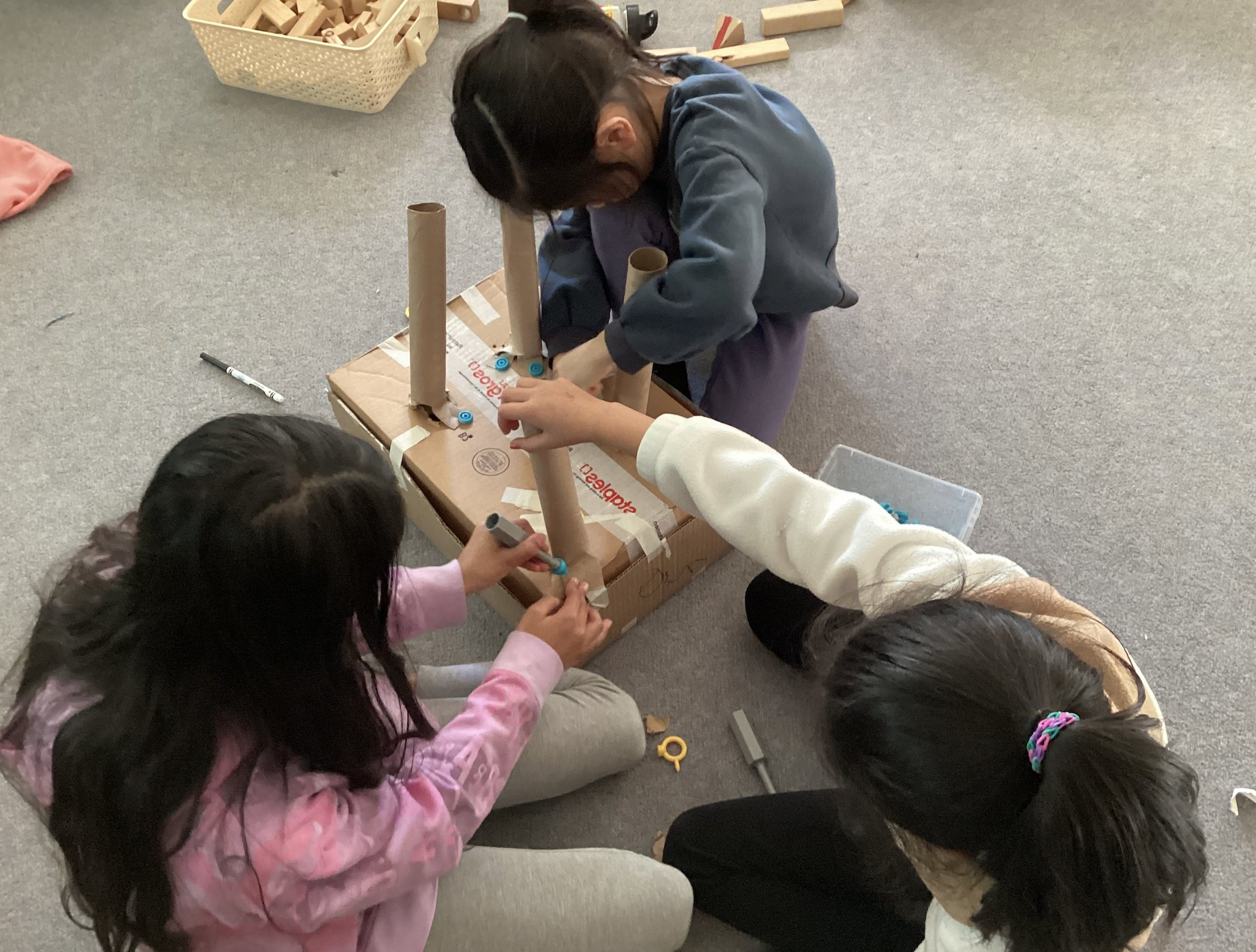 Kids assembling chairs with cardboard and paper materials